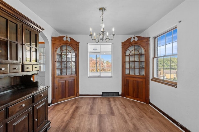 unfurnished dining area featuring a chandelier and light wood-type flooring