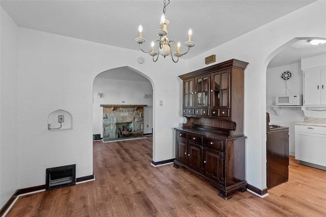 dining area featuring a stone fireplace, a chandelier, and hardwood / wood-style floors