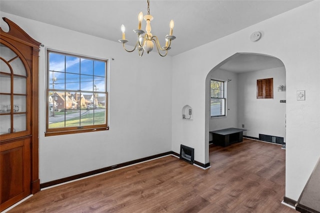 unfurnished dining area featuring a notable chandelier and wood-type flooring