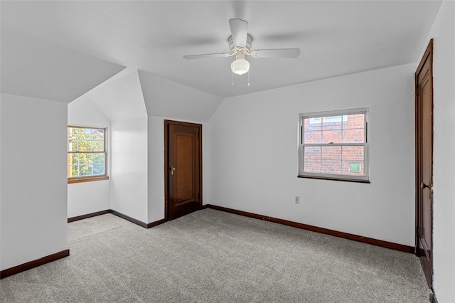 unfurnished bedroom with multiple windows, light colored carpet, vaulted ceiling, and ceiling fan