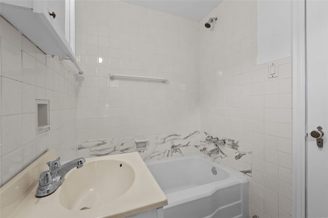 bathroom with tile walls, vanity, and tiled shower / bath