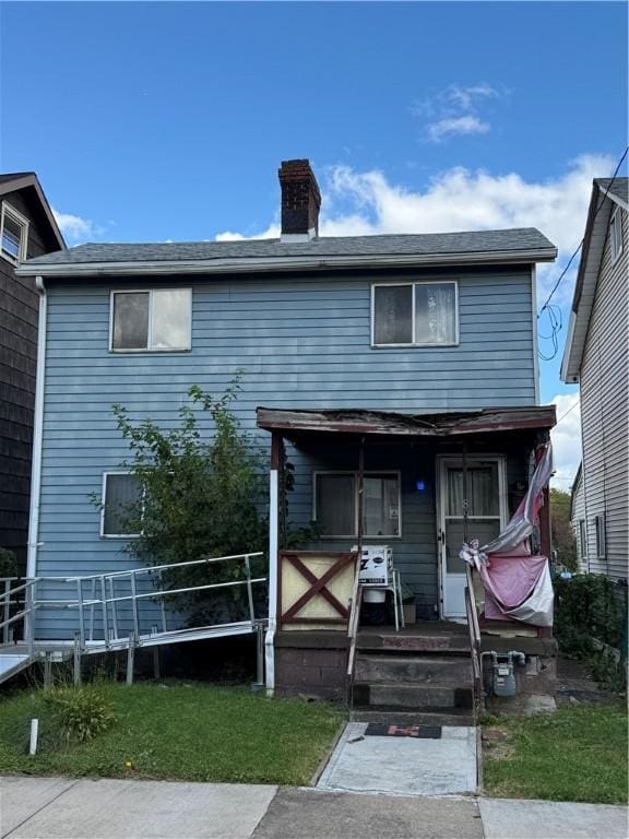 view of front facade featuring a chimney and a porch