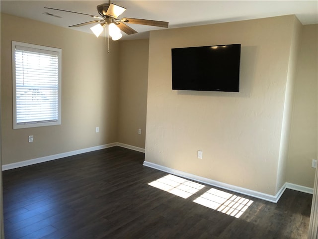 empty room featuring dark wood-type flooring and ceiling fan