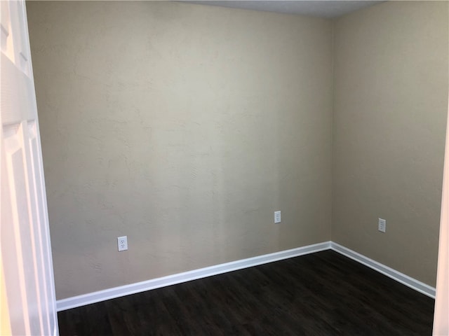 unfurnished room with dark wood-type flooring