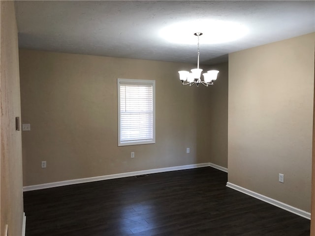 empty room featuring dark hardwood / wood-style flooring and a chandelier