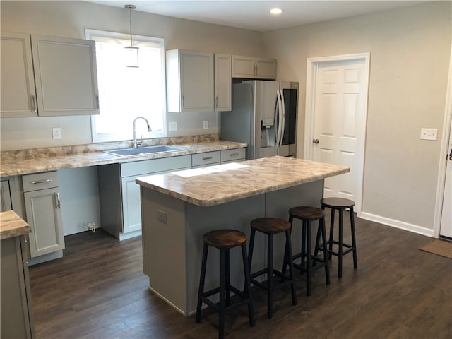 kitchen with decorative light fixtures, stainless steel fridge with ice dispenser, dark hardwood / wood-style floors, sink, and a center island