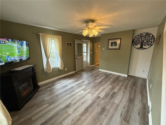 unfurnished living room with hardwood / wood-style floors, ceiling fan, and a textured ceiling