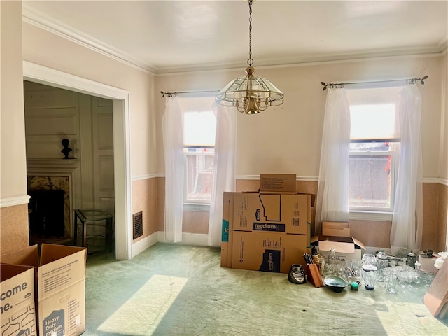 dining room with a chandelier, a wealth of natural light, crown molding, and light carpet