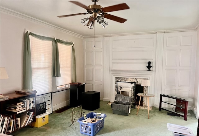 living area with crown molding, carpet, and ceiling fan