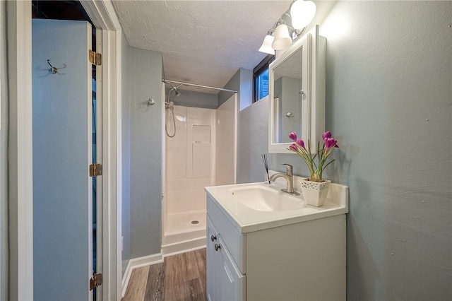 bathroom with vanity, walk in shower, wood-type flooring, and a textured ceiling