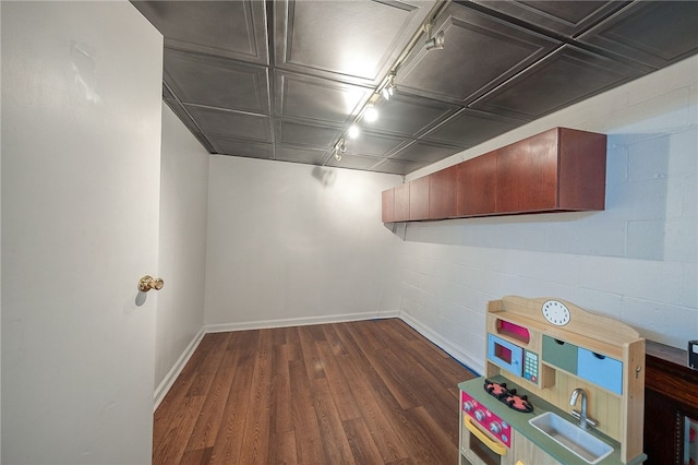 basement featuring track lighting and dark wood-type flooring