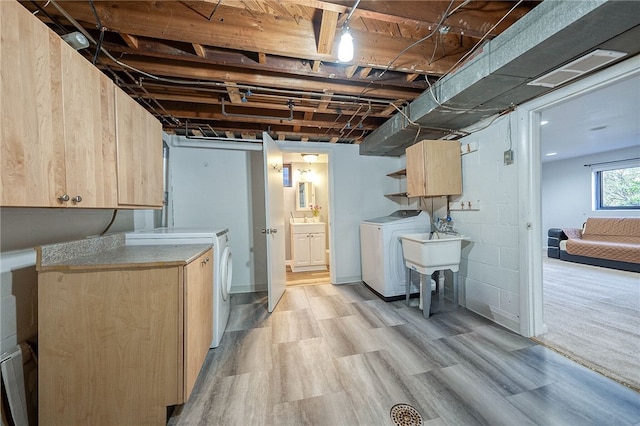 basement featuring light wood-type flooring, sink, and washer and dryer