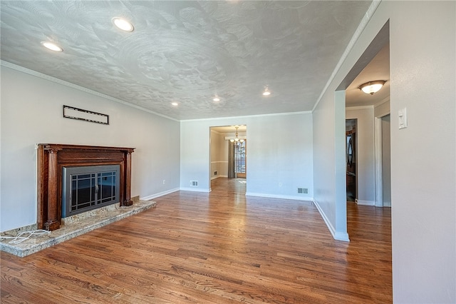 unfurnished living room featuring wood-type flooring, a notable chandelier, ornamental molding, and a textured ceiling