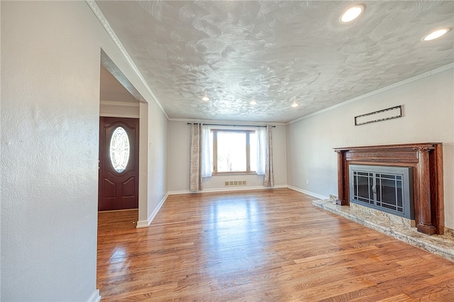 unfurnished living room featuring ornamental molding, light hardwood / wood-style floors, and a textured ceiling