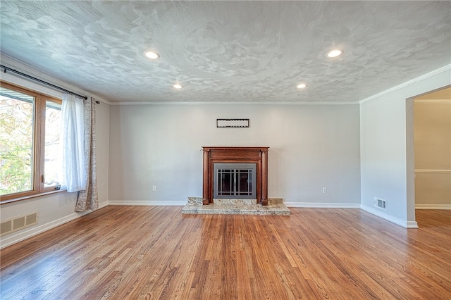 unfurnished living room with light hardwood / wood-style flooring, a textured ceiling, and crown molding