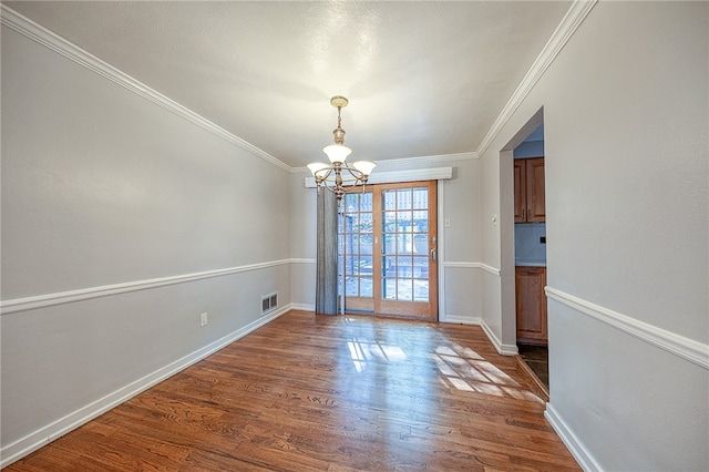 unfurnished dining area with dark hardwood / wood-style flooring, crown molding, and an inviting chandelier