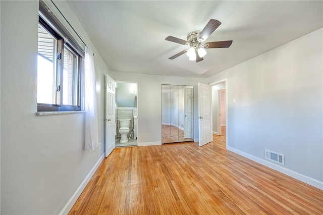 unfurnished bedroom with light hardwood / wood-style floors, ceiling fan, connected bathroom, and a closet