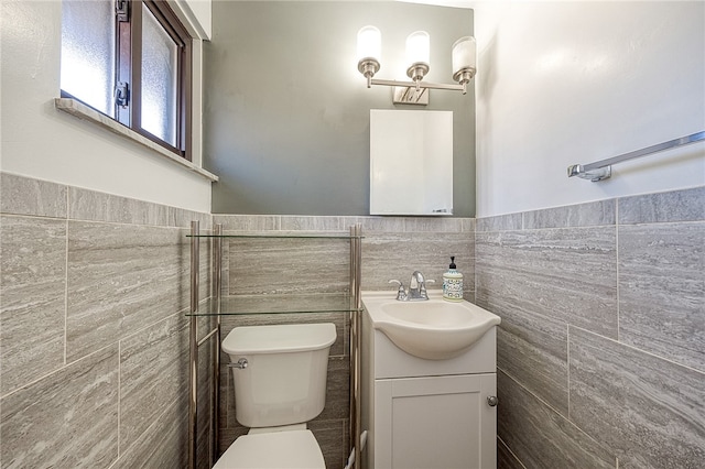 bathroom featuring vanity, toilet, and tile walls