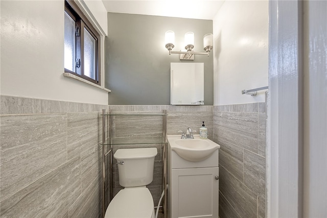 bathroom with toilet, vanity, and tile walls