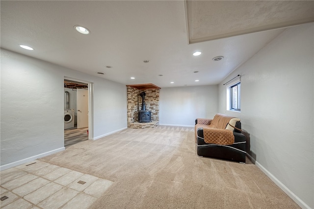 living area featuring a wood stove, washer / clothes dryer, and light carpet