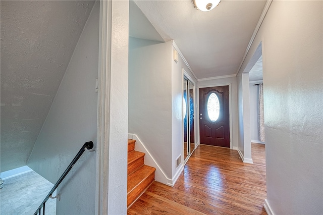 foyer with light wood-type flooring and crown molding