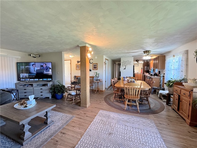 living room with ceiling fan, a textured ceiling, and light hardwood / wood-style flooring