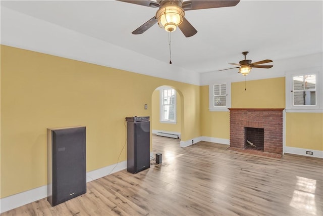 563 Coleman Ave, Greater Johnstown School District, PA 15902 - unfurnished living room featuring arched walkways, light wood-style flooring, baseboard heating, baseboards, and a ceiling fan