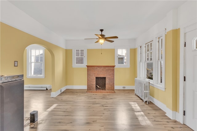 living room featuring a baseboard heating unit, radiator heating unit, light hardwood / wood-style floors, and plenty of natural light