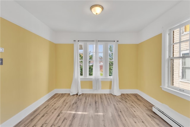 empty room with a baseboard radiator, light hardwood / wood-style flooring, and plenty of natural light