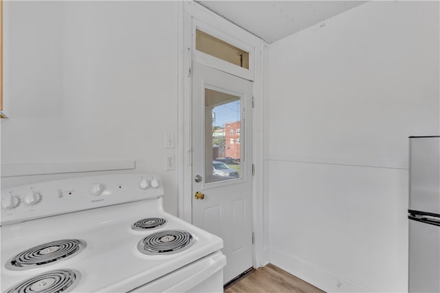 kitchen with refrigerator, light wood-type flooring, and white range with electric cooktop