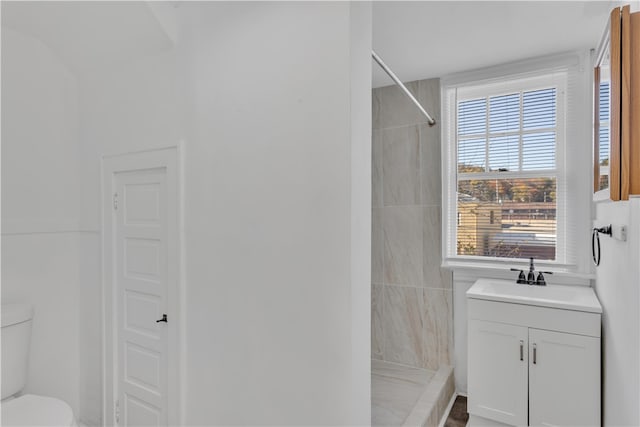 bathroom featuring a tile shower, toilet, and vanity