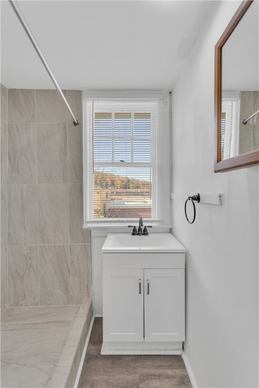 bathroom featuring a tile shower, hardwood / wood-style flooring, and vanity