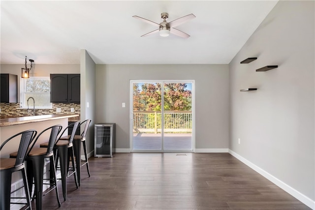 kitchen with decorative backsplash, ceiling fan, a kitchen breakfast bar, dark hardwood / wood-style floors, and sink