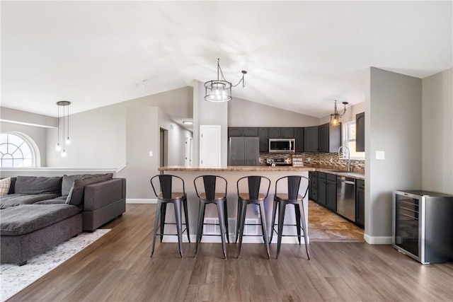 kitchen with hardwood / wood-style floors, lofted ceiling, a kitchen island, and appliances with stainless steel finishes