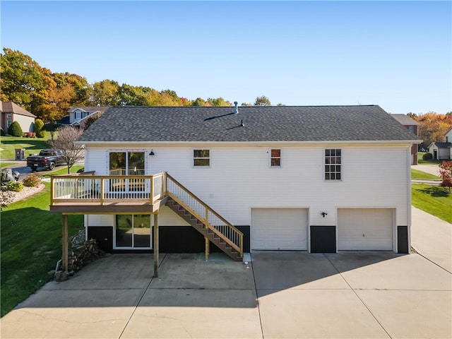 rear view of house featuring a wooden deck, a lawn, and a garage