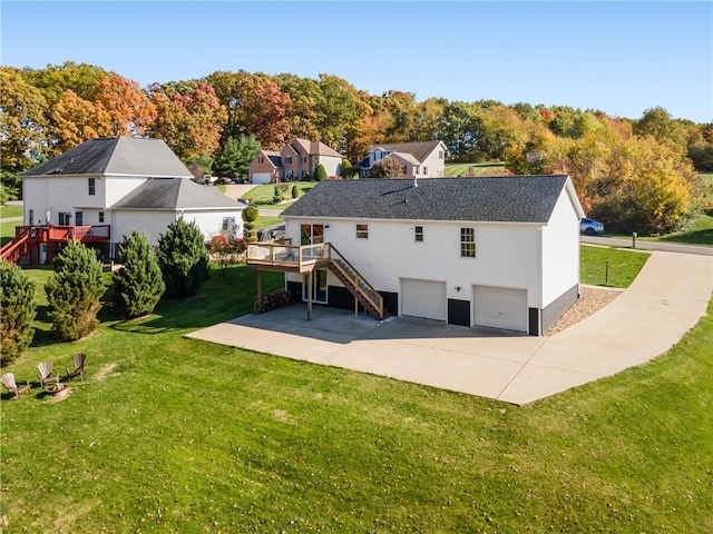 rear view of house featuring a deck, a lawn, and a garage