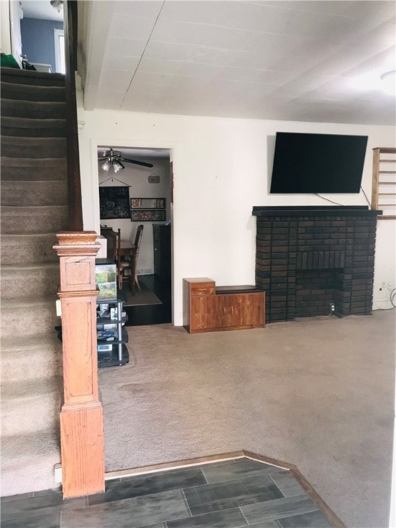 living room featuring dark carpet, a brick fireplace, and ceiling fan