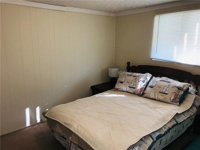 carpeted bedroom featuring wood walls and a textured ceiling