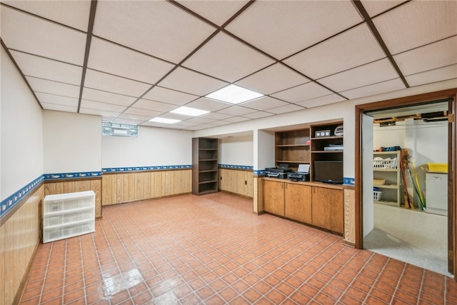 unfurnished office featuring a paneled ceiling and wooden walls