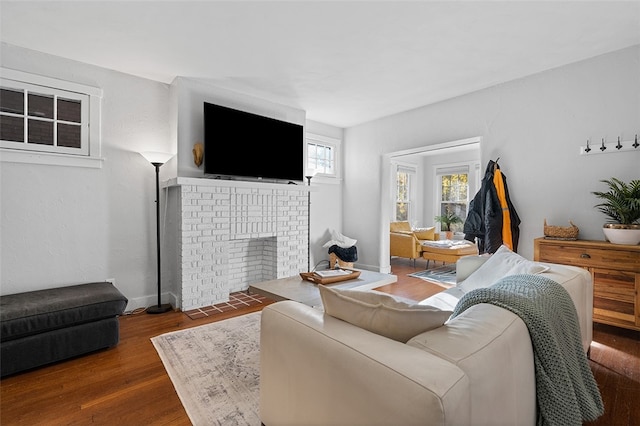 living room with dark wood-type flooring and a brick fireplace