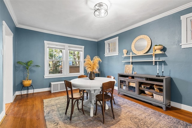 dining space featuring ornamental molding, radiator, and wood-type flooring