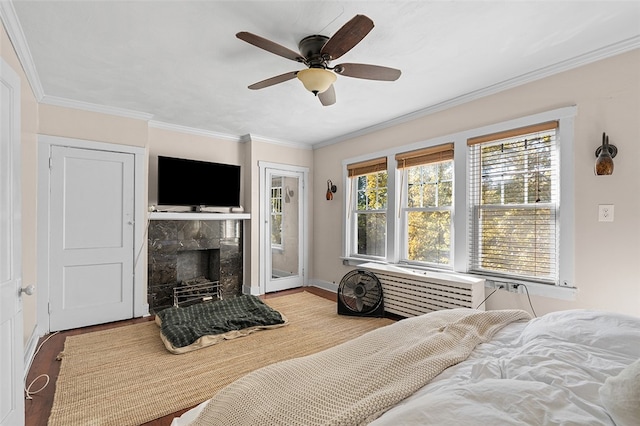 bedroom featuring ceiling fan, crown molding, light hardwood / wood-style floors, and a high end fireplace