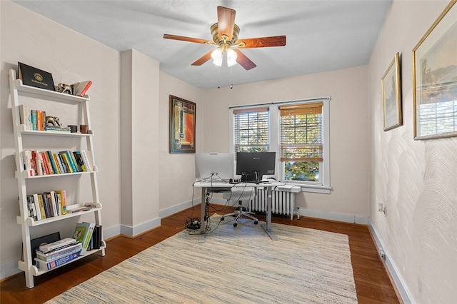 home office with ceiling fan, radiator heating unit, and dark hardwood / wood-style flooring