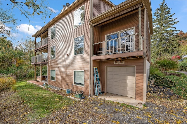 rear view of property featuring a balcony and a garage