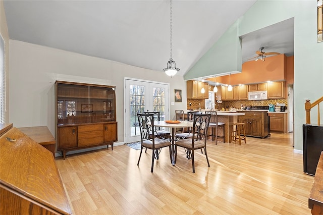 dining area with french doors, ceiling fan, high vaulted ceiling, and light wood-type flooring