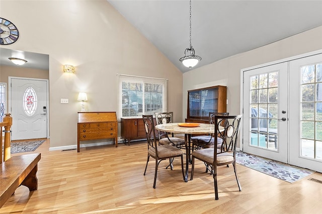 dining room featuring french doors, high vaulted ceiling, and light wood-type flooring