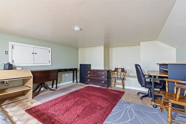 home office with vaulted ceiling and light wood-type flooring