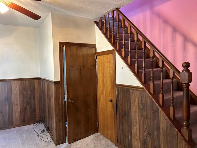 staircase with carpet flooring, ceiling fan, and a textured ceiling