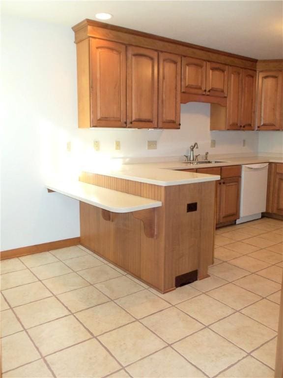 kitchen featuring kitchen peninsula, dishwasher, light tile patterned flooring, and sink