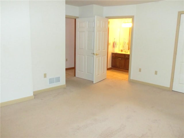 unfurnished bedroom with ensuite bathroom and light colored carpet